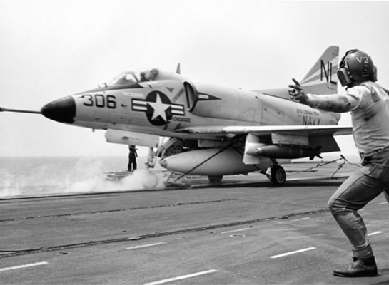 An officer gives the launch signal to the pilot of a Coral Sea &#40;CVA-43&#41; A-4 Skyhawk heading for a bo