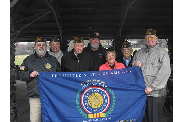 Vietnam veterans holding Vietnam War Commemoration flag.