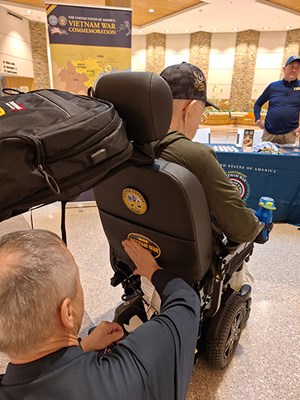 VWC's Henry Polczer applies a VWC bumper sticker on the motorized scooter of a Vietnam veteran. 