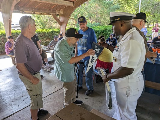 Navy personnel give out Navy items to veterans.