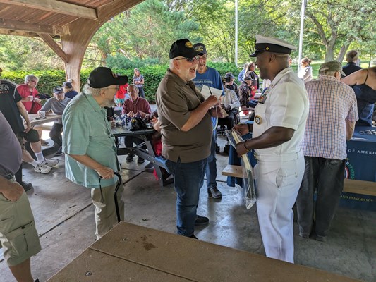 Navy personnel give out Navy items to veterans.