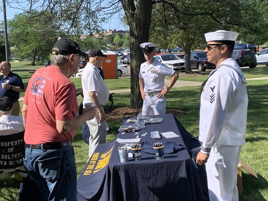 Navy personnel speak with visitors while handing out Navy items