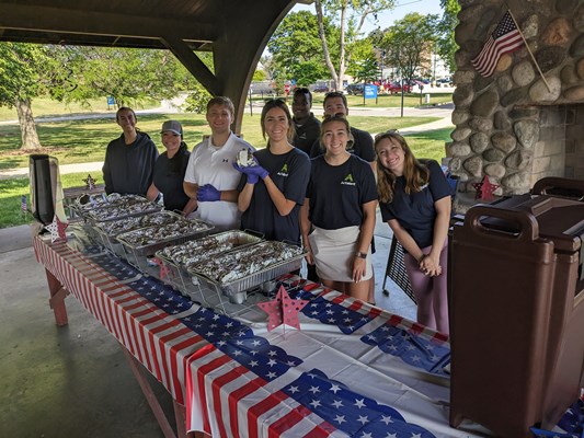 Event volunteers serve food during a cookout.