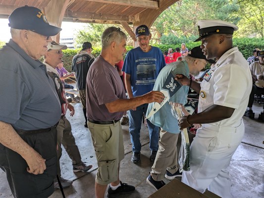 Navy personnel give out Navy items to veterans.