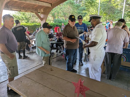 Navy personnel give out Navy items to veterans.