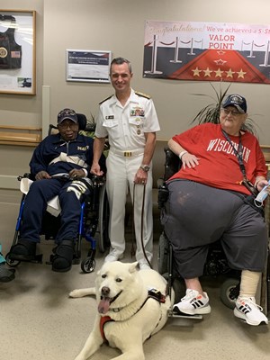 5Rear Adm. Douglas G. Perry takes a photo with two veterans and a service dog.