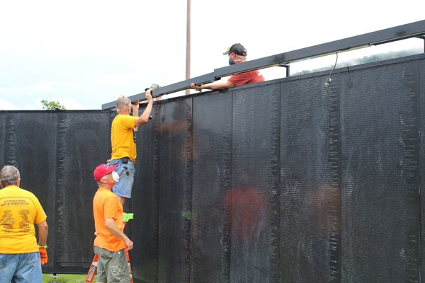 Volunteers and staff help assemble The Wall That Heals