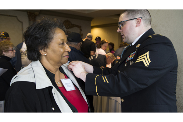 A nurse who served during the Vietnam War is pinned by Vietnam War Commemoration staff member.
