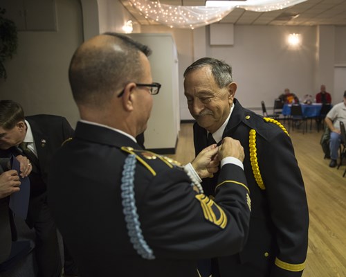 SFC Ralph Walton, of the U.S.A. Vietnam War 50th Commemoration, pins a Vietnam veteran.