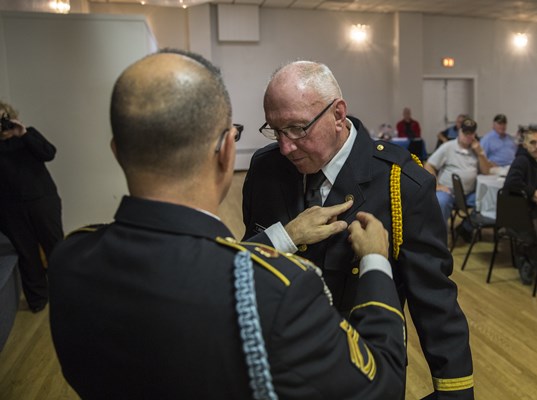 SFC Ralph Walton, of the U.S.A. Vietnam War 50th Commemoration, pins a Vietnam veteran.
