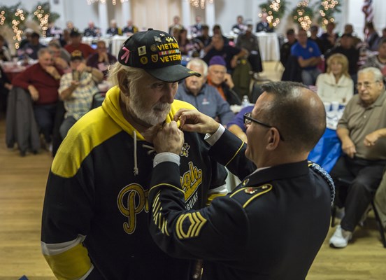 SFC Ralph Walton, of the U.S.A. Vietnam War 50th Commemoration, pins a Vietnam veteran.