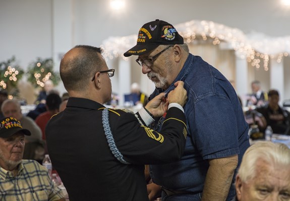 SFC Ralph Walton, of the U.S.A. Vietnam War 50th Commemoration, pins a Vietnam veteran.