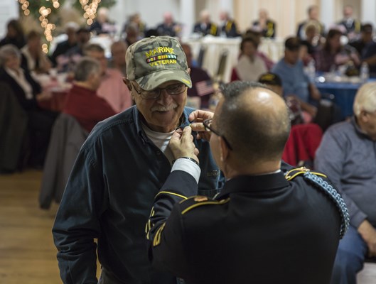 SFC Ralph Walton, of the U.S.A. Vietnam War 50th Commemoration, pins a Vietnam veteran.