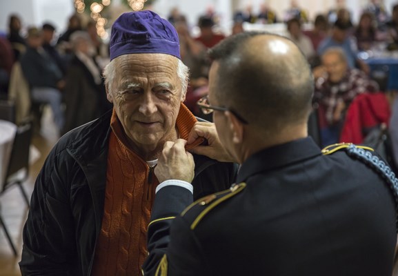 SFC Ralph Walton, of the U.S.A. Vietnam War 50th Commemoration, pins a Vietnam veteran.