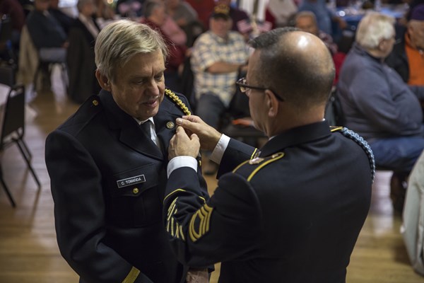 SFC Ralph Walton, of the U.S.A. Vietnam War 50th Commemoration, pins a Vietnam veteran.