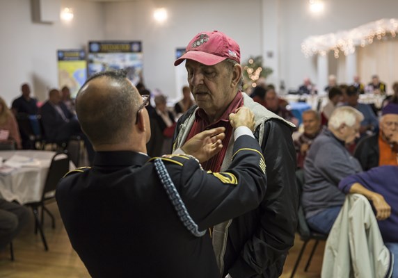 SFC Ralph Walton, of the U.S.A. Vietnam War 50th Commemoration, pins a Vietnam veteran.