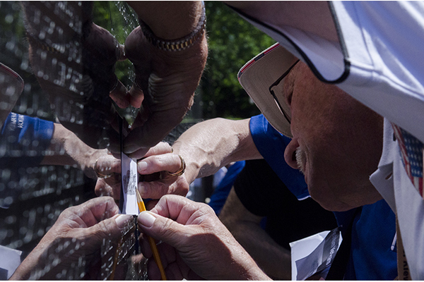 Two veterans trace name of fellow veteran.