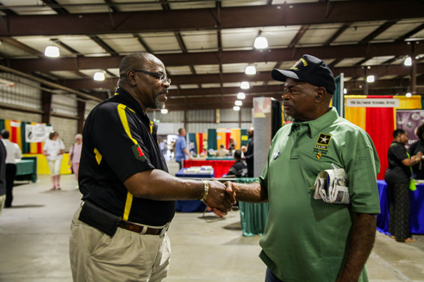 Two Vietnam veterans shake hands after meeting at the Vietnam War Commemoration&#39;s display booth.