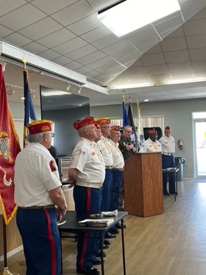 Director Chrystal speaks at the podium beside members of the Detachment.