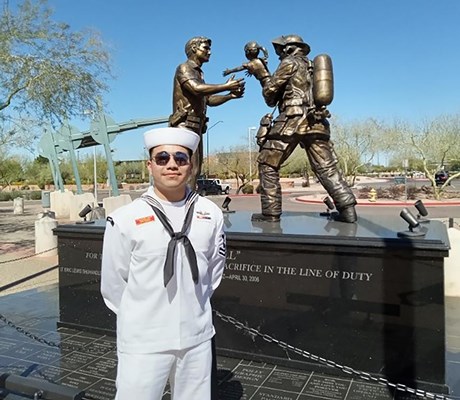 Petty Officer 2nd Class Romero poses in front of the Gilbert Police Dept. memorial.
