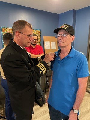Cmdr. Brian Wierzbicki, U.S. Navy, VWC Chief, Public Engagement, pins a Vietnam veteran.