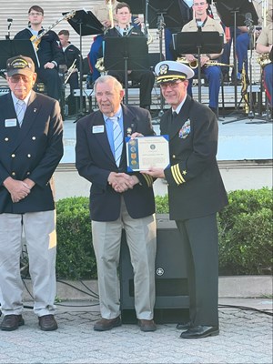 Photo of Cmdr. Brian Wierzbicki, USN, and Chief, Public Engagement as he presents a certificate. 