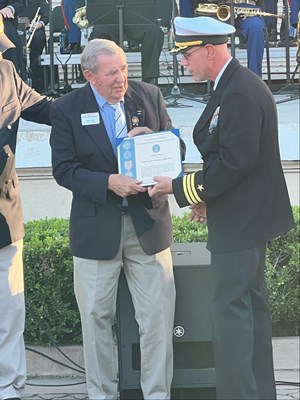 Photo of Cmdr. Brian Wierzbicki, USN, and Chief, Public Engagement as he presents a certificate. 