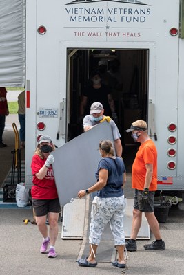 Event volunteers and staff unload The Wall That Heals components from the trailer for event set up