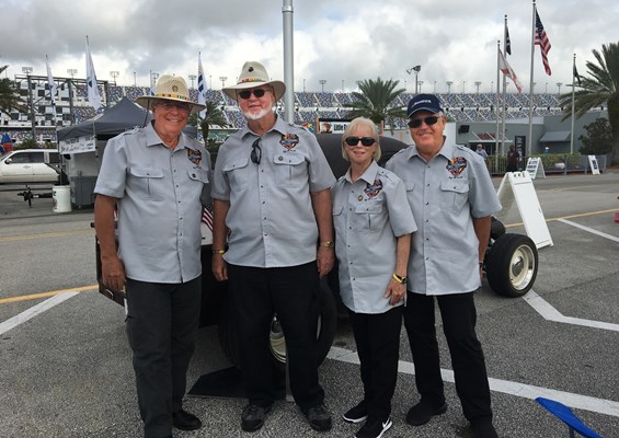 Four members of the Vietnam Veterans Tribute Truck pose in uniform — two with their Vietnam veteran 