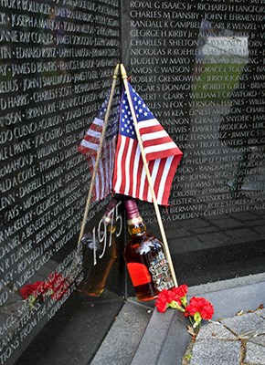 An American flag, a flower and a bottle of Scotch lean against the Vietnam Veterans Memorial after a
