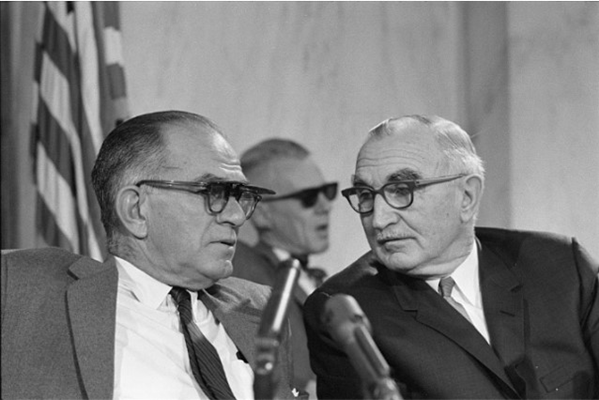 Senator Wayne Morse (right) seated with Senator William Fulbright in front of microphones during a h