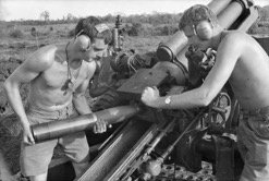 Two artillerymen load a 105-millimmeter shell into a howitzer cannon, November 1967. (Australian War Memorial)