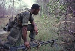 An African American soldier waits at the edge of the tree line somewhere in South Vietnam, unknown date. African Americans served disproportionately in combat units. (Texas Tech University Vietnam Center and Archive)