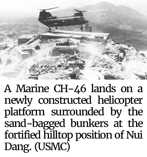 Photo of a Marine CH-46 landing on a newly constructed helicopter platform surrounded by the sand-bagged bunkers at the fortified hilltop position of Nui Dang. (USMC)