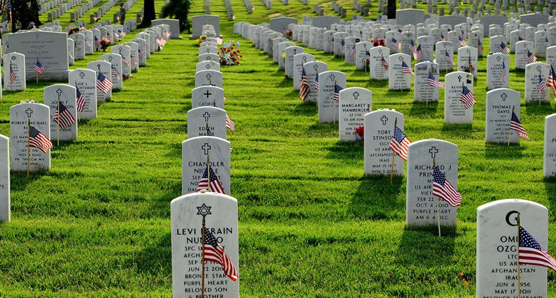 Photo of a Veterans Cemetery with small U.S. flags placed in front of the headstones.