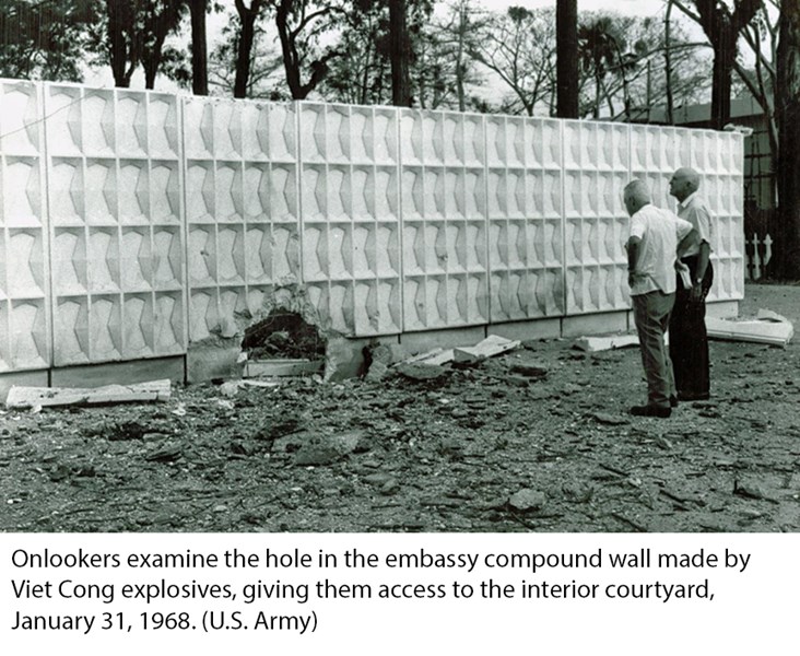 Onlookers examine the hole in the embassy compound wall made by Viet Cong explosives, giving them access to the interior courtyard, January 31, 1968. (U.S. Army)