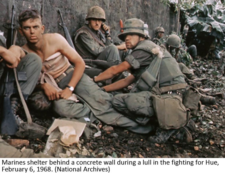 Marines shelter behind a concrete wall during a lull in the fighting for Hue, February 6, 1968. (National Archives)