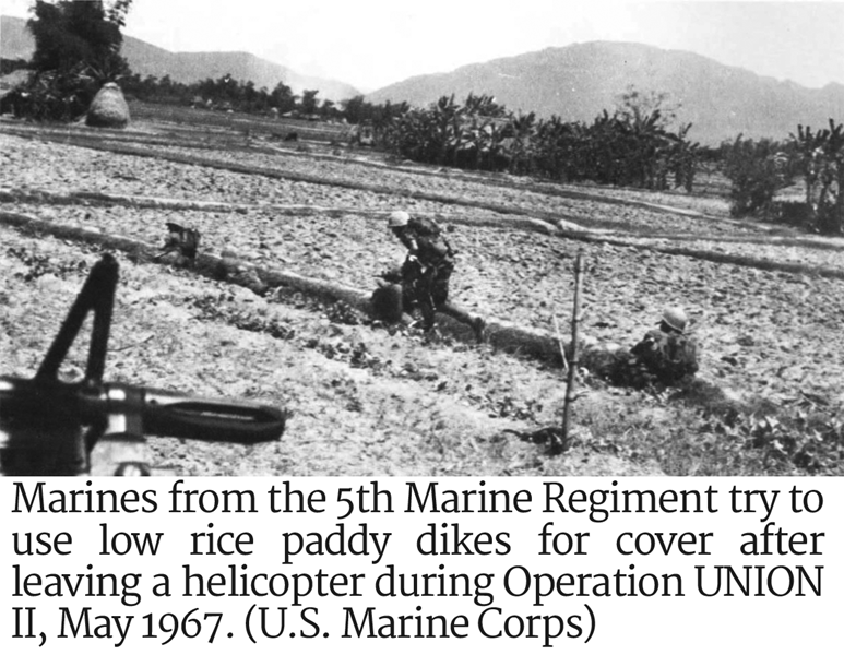 Photo of Marines from the 5th Marine Regiment try to use low rice paddy dikes for cover 