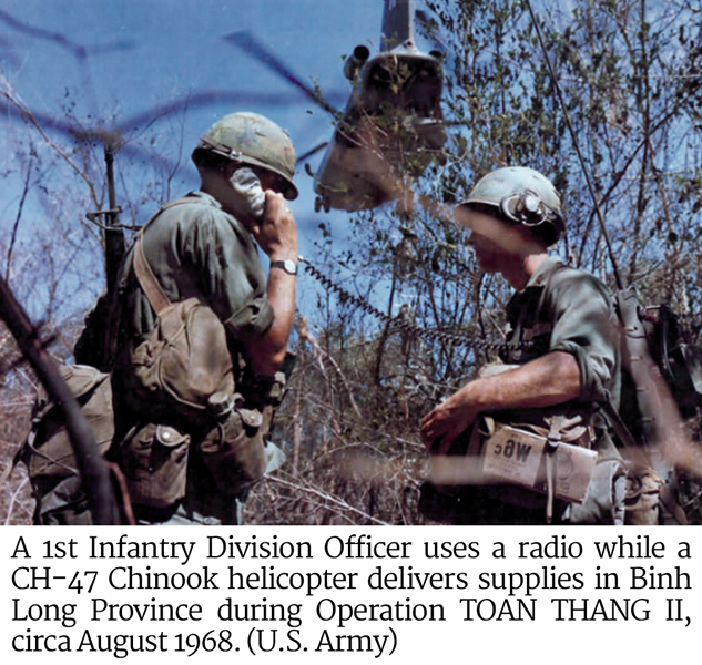 A 1st Infantry Division Officer uses a radio while a CH-47 Chinook helicopter delivers supplies in Binh Long Province during Operation TOAN THANG II, circa August 1968. 