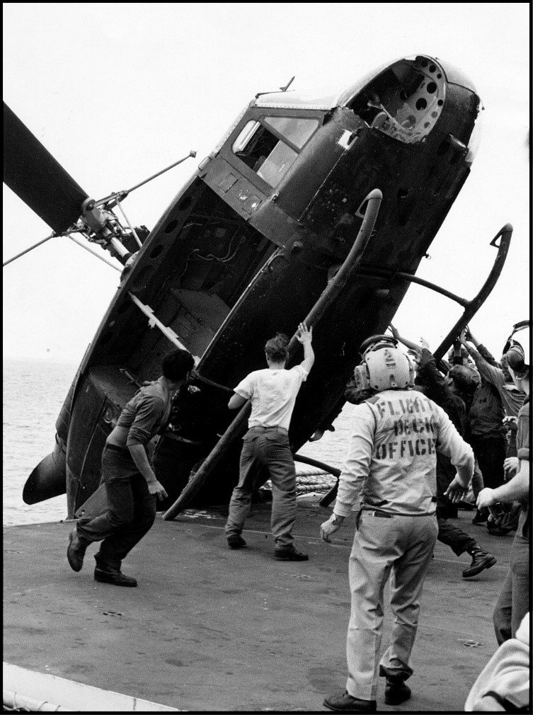 U.S. servicemen push a South Vietnamese helicopter over the side of the USS Okinawa, which had just evacuated five Vietnamese refugees from Saigon, to make room on the crowded flight deck for more aircraft, April 29, 1975.